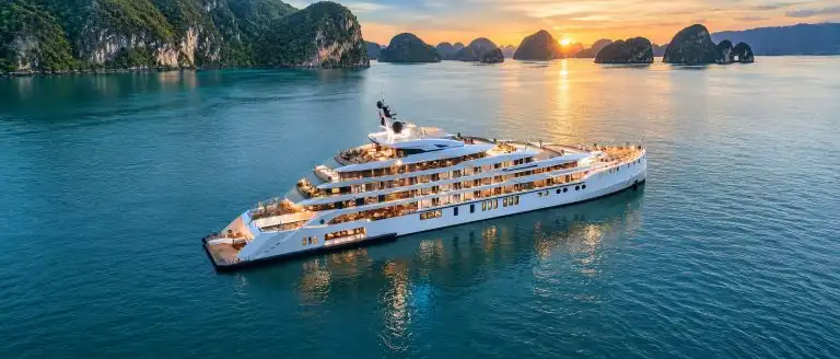 Grand Pioneers luxury cruise sailing through Ha Long Bay at sunset